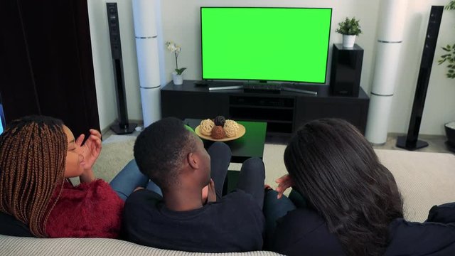 Three african friends watch television in living room and they are crying 
