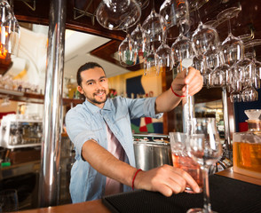 Handsome young smiling barman is preparing alcoholic drink.