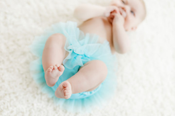 Closeup of legs and feet of baby girl on white background wearing turquoise tutu skirt. © Irina Schmidt