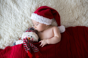 Little sleeping newborn baby boy, wearing Santa hat