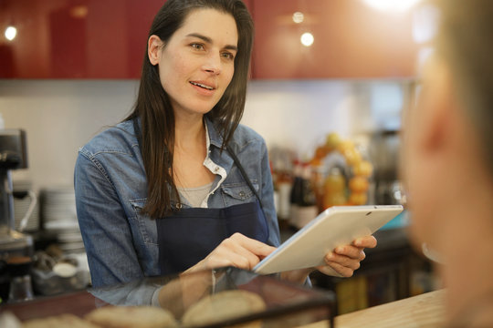 Waitress in coffee shop taking order on digital tablet