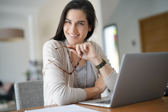 Cheerful woman working on laptop at home-office