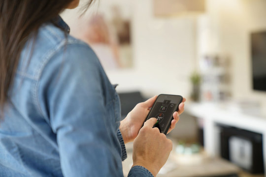 Woman using remote home control system on smartphone