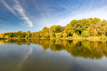 Beautiful autumn lake landscape. Colorful trees and blue sky