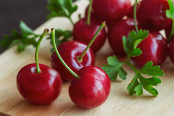 Close up fresh red cherries on wood cutting board in side view. Cherry have high vitamin C and have sweet and sour taste. Healthy fruit background and wallpaper concept.