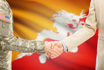 USA military man in uniform and civil man in suit shaking hands with adequate national flag on background - Bhutan