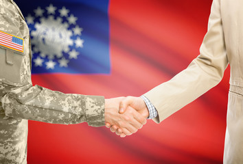 USA military man in uniform and civil man in suit shaking hands with adequate national flag on background - Burma