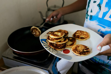 Young woman frying pancakes for breakfast at home in kitchen