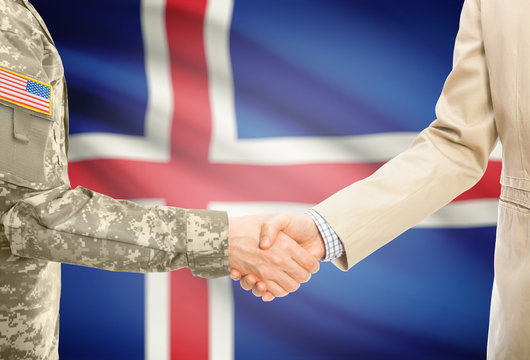 USA military man in uniform and civil man in suit shaking hands with adequate national flag on background - Iceland