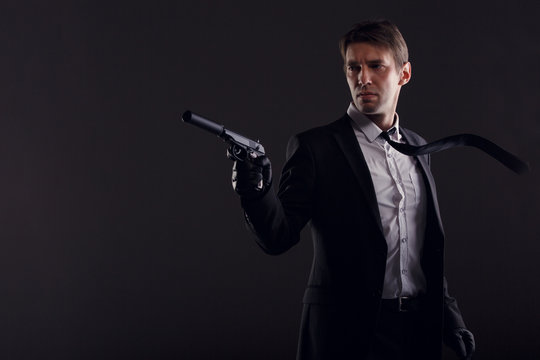 Portrait of man in leather gloves with gun isolated on black background.