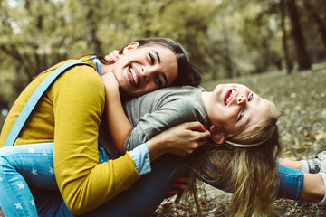 Mother and daughter outdoors in a meadow. Little girl lying on mother lap.