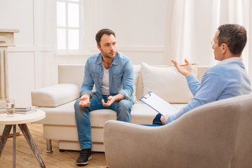 Psychologist advice. Lost upset unhappy man consulting with psychologist who sitting and holding...