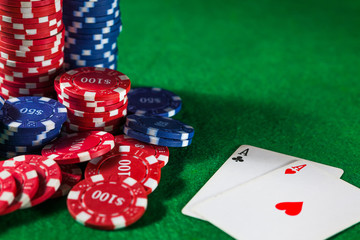Close up of casino chips and two ACE cards on green table