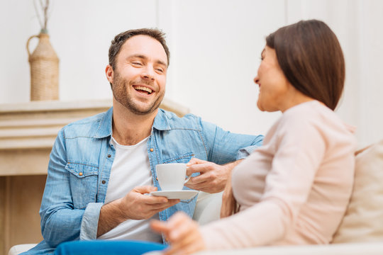 Sincere laugh. Positive nice optimistic man has fun with woman while sitting and enjoying coffee 