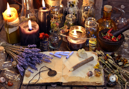 Open book with healing herbs, lavender flowers, candles, potion bottles and magic objects. Occult, esoteric, divination and wicca concept. Mystic, old apothecary and vintage background