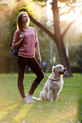 Picture of young brunette on walk with dog in summer park