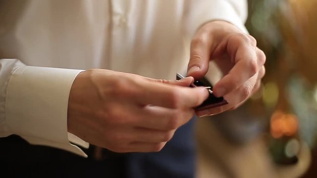 businessman puts on cufflinks