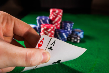 Poker chips with two aces on green background.