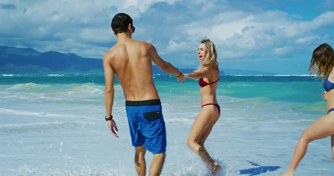 Attractive young people walking down the beach laughing and having fun