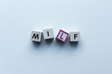 Obraz premium top view of wooden cubes with word Milf on blue tabletop