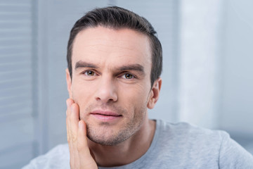 Obraz premium Accurate observation. Amazing young calm man touching his chick gazing at the camera while making conclusions 