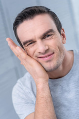 Obraz premium Cute moments. Enthusiastic motivated nice man scraping his chick while putting his head on his palm and grimacing