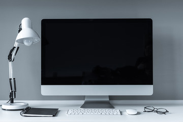 working place with computer and switched off table lamp