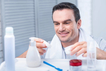 Perfect skin. Nice young  attractive man  looking how he  opening lotion for applying on the skin