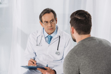 doctor holding clipboard and listening patient