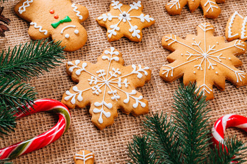 Christmas gingerbread cookies homemade with branches of Christmas tree and New Year decor on table with burlap tablecloth. Merry Christmas postcard.