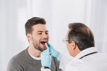 doctor examining patient throat in medical gloves