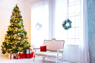 Christmas living room with a Christmas tree, sofa, gifts and a large window. Beautiful New Year decorated classic home interior