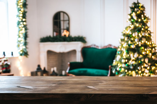 Christmas holiday background with empty rustic table and the bokeh of the living room with the Christmas tree, sofa and fireplace on the second plan - Powered by Adobe
