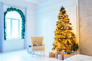 Christmas living room with a Christmas tree, sofa, gifts and a large window. Beautiful New Year decorated classic home interior