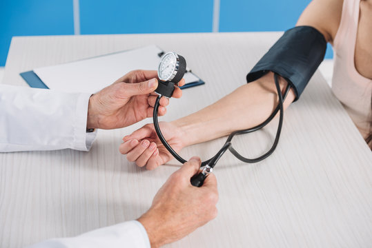 cropped image of doctor measuring female patient pressure