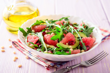 Fresh salad with arugula, grapefruit, avocado, pomegranate seeds and pine nuts.