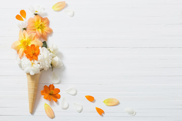 flowers in waffle cone on white wooden background