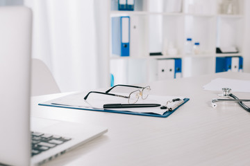 glasses and pen on clipboard on working table in clinic