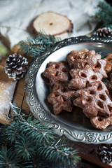 gingerbread cookies for the new year and Christmas on a silver tray, Christmas tree, cones, cinnamon on a wooden cutting board on a dark background
