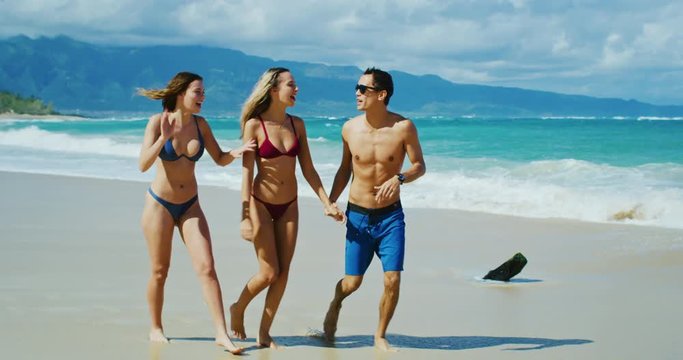 Attractive young people walking down the beach laughing and having fun