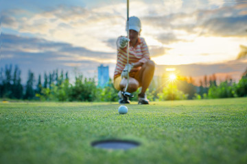 Golf ball in line measurement and culculating for the best resulted by golf player in background, ball on the green of golf course with early light of sunset in background