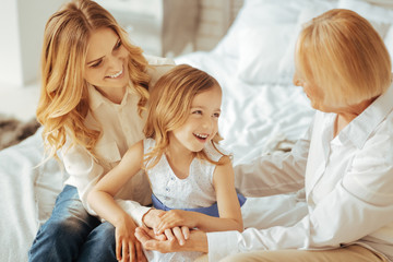 Obraz na płótnie Canvas Family relationships. Happy delighted cute girl smiling and having fun while spending time with her family