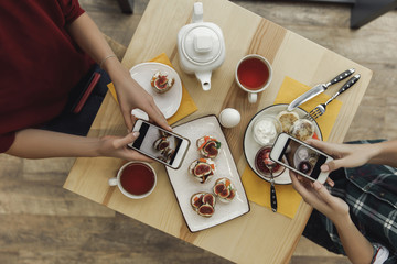 top view of people using smartphones and photographing appetizers during breakfast