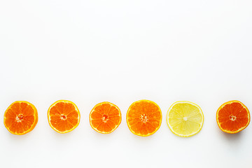 a row of tangerines and one lemon on a white background.