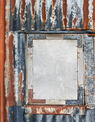 boarded window in rust and grey corrugated iron wall abandoned outbuilding