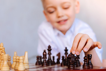 Chess game. Selective focus of a chess piece being held by a nice smart cheerful boy while playing chess