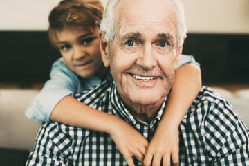 Portrait of grandson embracing happy grandfather