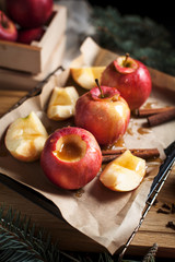 cooking of baked apples for New Year's holidays, Christmas tree and New Year's lights, honey and cinnamon on a wooden cutting board on a dark background