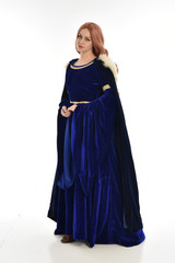 full length portrait of girl wearing long blue velvet gown and fur lined cloak, standing pose  on white background.