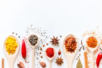 Fotobehang Spoons with condiments and spices on a white background with space for text © itakdalee